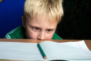 Frustrated boy with head on table unable to concentrate on his homework