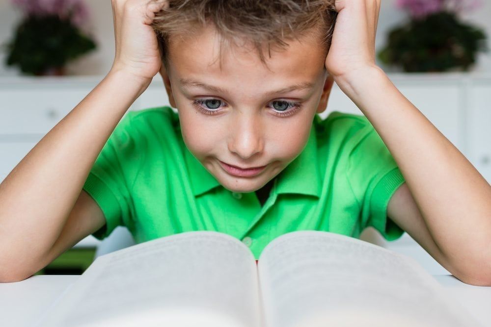 Child with learning disorder, frustrated in front of book