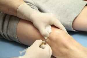 Injection being administered to a patients knee to treat inflammation