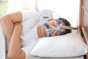 Sleep apnea therapy,Man sleeping in bed wearing CPAP mask.