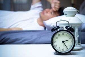 Man laying awake in bed at 2:30am because of a sleeping disorder